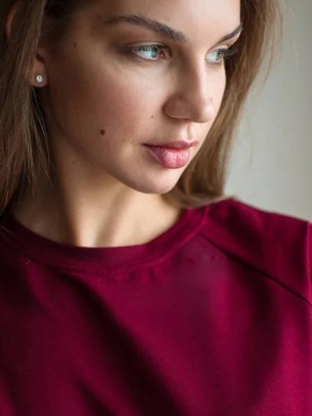 Foto de moda de una hermosa morena sonriente en un suéter rojo posando sobre un fondo gris vacío . —  Fotos de Stock