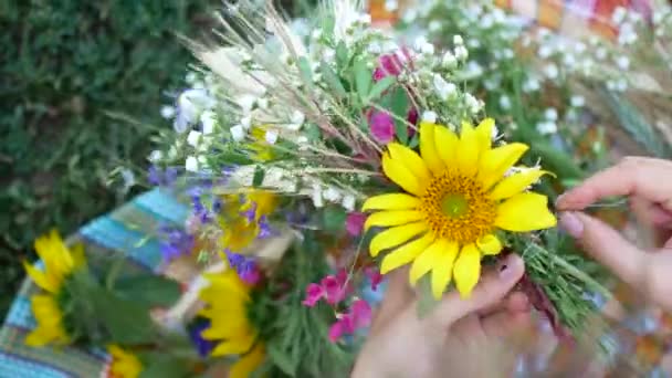 Kvinnliga händer gör en krans av vilda blommor sommar — Stockvideo