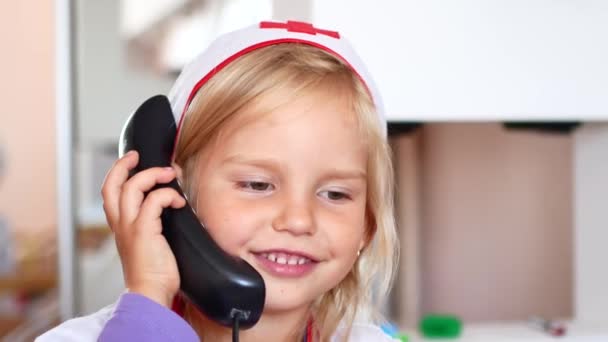 Маленька дівчинка грає у лікаря. медсестра приймає дзвінок — стокове відео