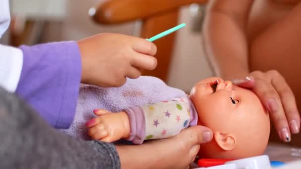 Ein aktives kleines Vorschulkind, ein hübsches kleines Mädchen mit blonden Haaren, spielt mit ihren Puppen. Den Arzt spielen — Stockvideo