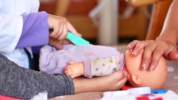 Una niña preescolar activa, una niña bonita con el pelo rubio, juega con sus muñecas. Jugando al Doctor — Vídeos de Stock