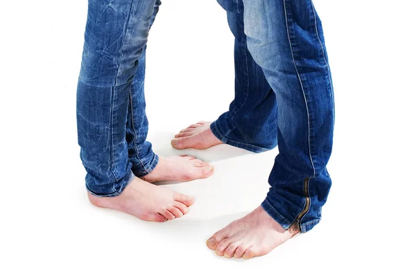 Nuori pari paljain jaloin jalat yllään sininen farkut eristetty valkoisella taustalla — kuvapankkivalokuva