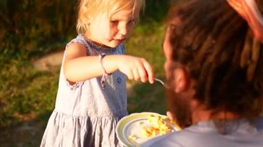 Küçük bir kız babası bir kaşık ile besleniyor. Köyün yaz akşamları