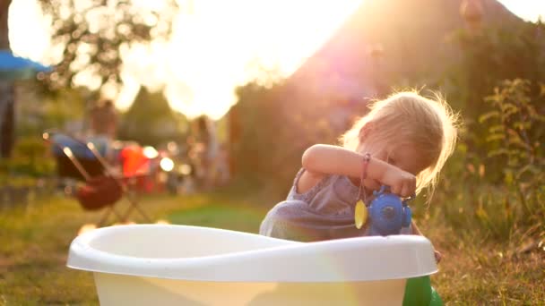 Crianças alegres felizes brincando com água nas férias de verão. Bonito adorável sorrindo crianças pulverizando com uma mangueira de jardim no quintal. Fechar — Vídeo de Stock