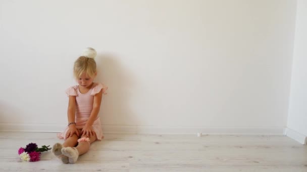 Young dancer warming up on the floor, a bouquet of flowers lies nearby. — Stock Video