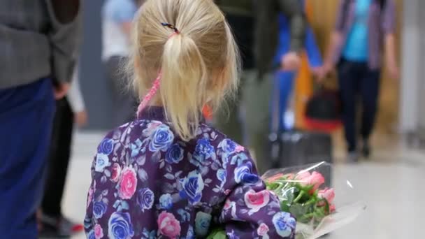 Niña con un ramo de rosas en el salón del aeropuerto — Vídeos de Stock