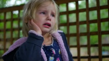 Küçük kız çardak içinde ağlıyor. Sonbahar yağmurlu bir gün