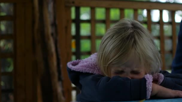 Маленькая девочка плачет в беседке. Осенний дождливый день — стоковое видео