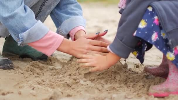 遊んでいる子供たちはビーチで砂します。少女は、ビーチで自分で砂の城を構築します。. — ストック動画