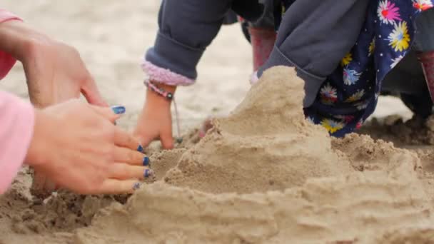 Spelende kinderen zand op het strand. Meisje bouwt zandkasteel door hemzelf op het strand. — Stockvideo