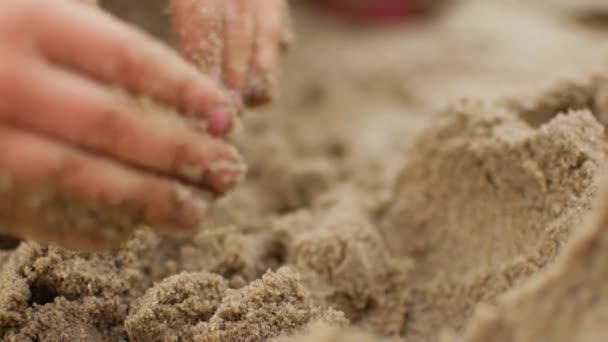 Niños jugando a la arena en la playa. Niña construye castillo de arena por sí mismo en la playa . — Vídeos de Stock