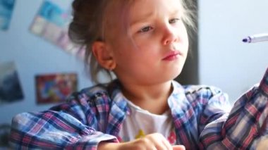 Sevimli küçük kız oturur onun tablo ve boya kalemi ile berabere.