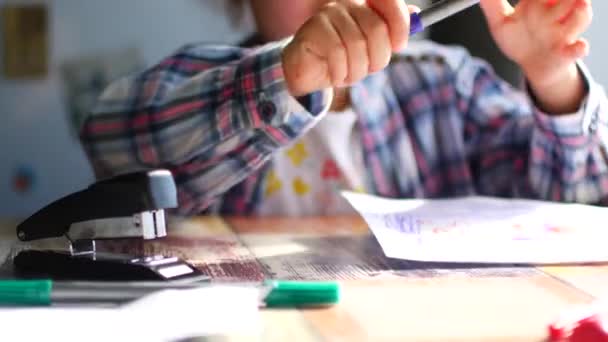 Schattig klein meisje zit aan haar tafel en trekt met kleurpotloden. — Stockvideo