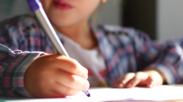 Carino bambina si siede al suo tavolo e disegna con pastelli . — Video Stock