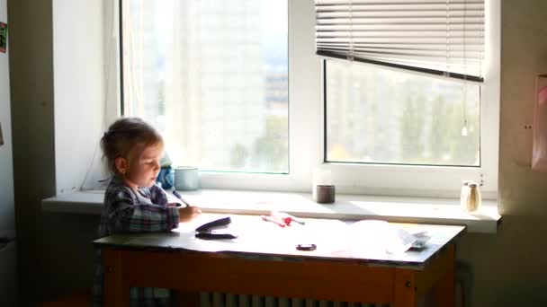 Menina bonito senta-se em sua mesa e desenha com lápis de cera . — Vídeo de Stock
