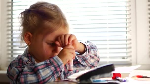 Linda niña se sienta a su mesa y dibuja con lápices de colores . — Vídeos de Stock