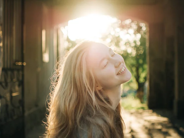 Rusovlasá mladá dívka v paprscích zapadajícího slunce. Portrét města — Stock fotografie