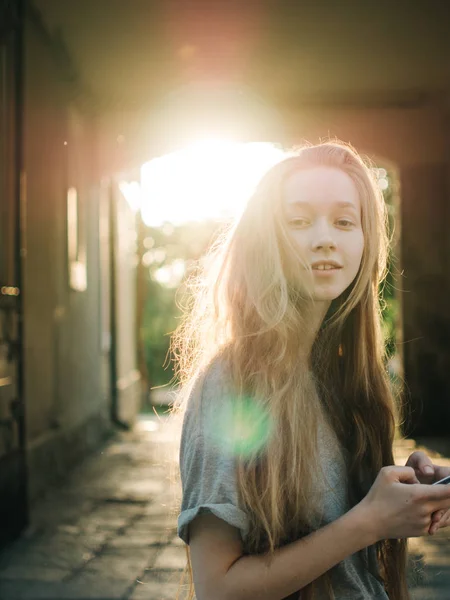 Red-haired young girl in the rays of sunset. City portrait Stock Image
