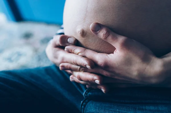 Schwangere kuschelt Bauch im Schlafzimmer zu Hause kurz vor den Wehen und der Geburt, selektiver Fokus — Stockfoto