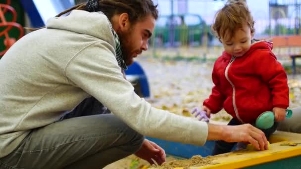 A criança toca as estatuetas de areia com a mão. Close-up. A menina está brincando na caixa de areia . — Vídeo de Stock