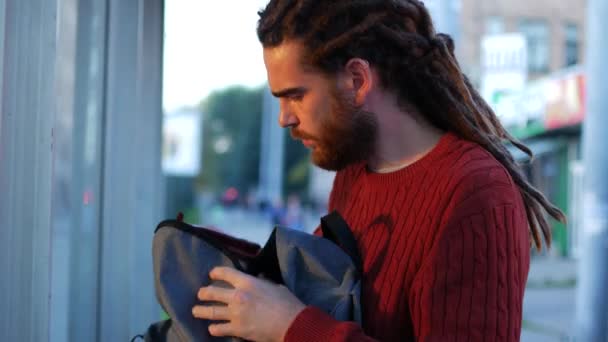 Hombre de moda. Joven alegre con mochila disfrutando paseando por la ciudad — Vídeo de stock