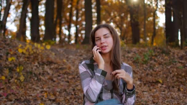 Flicka i gul skogen. Kvinnan pratar i telefon i skogen höst. — Stockvideo