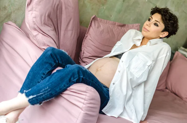 Vacker gravid kvinna sitter på soffan hemma — Stockfoto