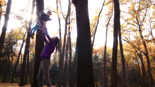 Закритий батько грає зі своєю маленькою донькою в осінньому лісі — стокове відео