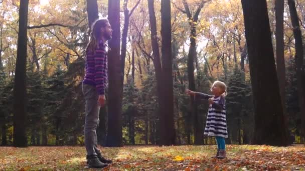 Papá y su hija están jugando en el bosque de otoño. Papá atrapa al bebé. — Vídeo de stock