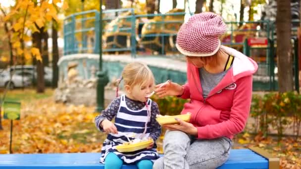 Mamma och dotter har lunch i parken på en höst eftermiddag. Kärlek, Familj, mat — Stockvideo