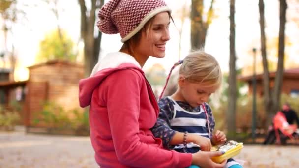 Mom and daughter have lunch in the park on an autumn afternoon. Love, family, food — Stock Video
