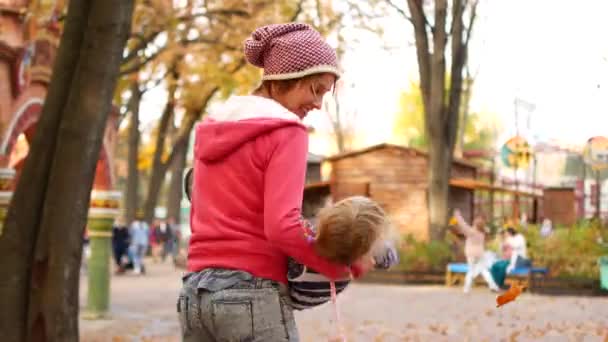 Mamma virvlar sin dotter i famnen i parken. Höstdag — Stockvideo