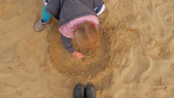 A rapariga está a brincar na caixa de areia. A caixa de areia, um pouco de loira esculpe figuras de areia . — Vídeo de Stock