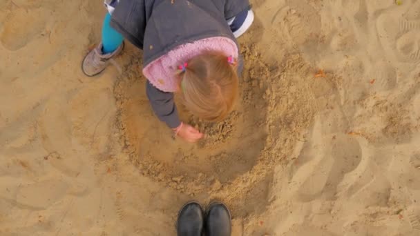 La ragazza sta giocando nella sabbiera. La sabbiera, una piccola bionda Sculpts Figurines From Sand . — Video Stock