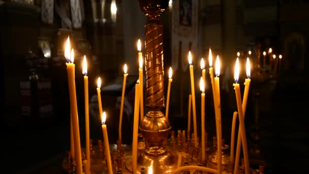 Primer plano de la vela encendida en el fondo de otras velas en la Iglesia Ortodoxa Cristiana — Vídeo de stock