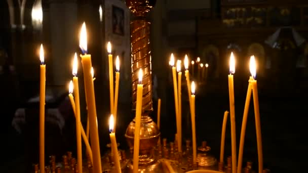 Primer plano de la vela encendida en el fondo de otras velas en la Iglesia Ortodoxa Cristiana — Vídeos de Stock