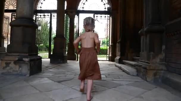 Una bambina corre attraverso l'arco di un vecchio castello — Video Stock