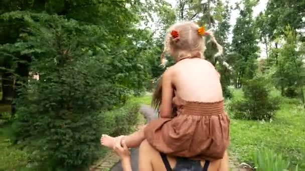 Feliz mamá lleva hermosa hijita en sus hombros, caminar en el parque con el niño , — Vídeos de Stock