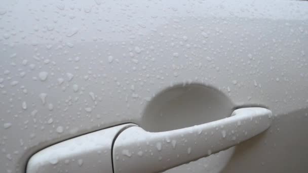 Γκρο πλαν, σχετικά με το αυτοκίνητο. σταγόνες βροχής σε τη λαβή της πόρτας του ένα άσπρο αυτοκίνητο — Αρχείο Βίντεο