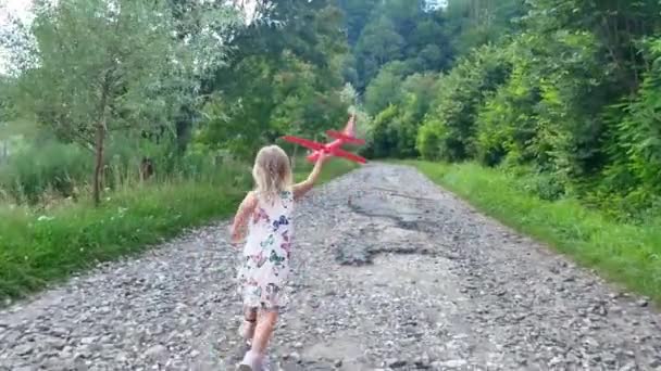 可爱的小女孩孩子玩飞机玩具在公园日落黄金小时童年天真玩概念慢动作射击 — 图库视频影像
