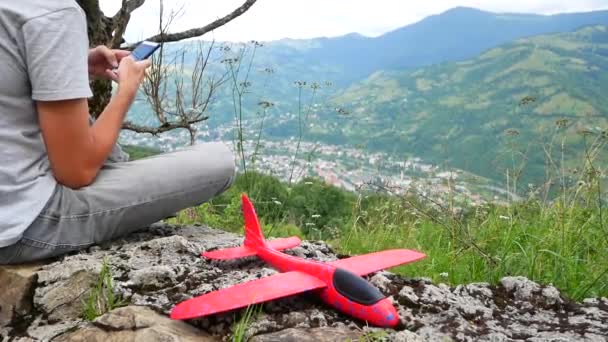 Rapaz caucasiano a brincar com um avião modelo. Retrato de uma criança com um avião de madeira em um campo. Menino na natureza brinca com o layout da aeronave . — Vídeo de Stock