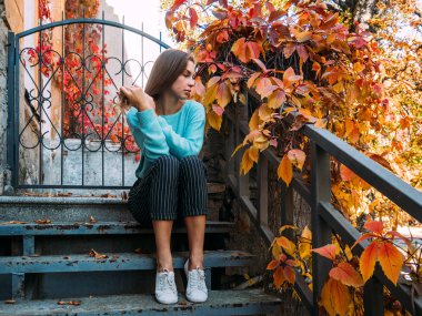 Sonbahar manzara zevk güzel genç kız veranda basamaklarında oturan bir mavi süveterli.