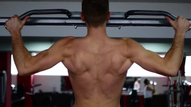 In de sportschool maakt een man schommels met gespierde armen — Stockvideo