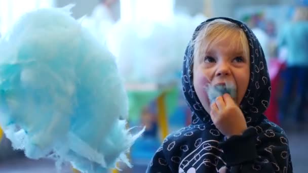 Malá holčička v kapuci jí modrá cukrová vata v cirkusu — Stock video