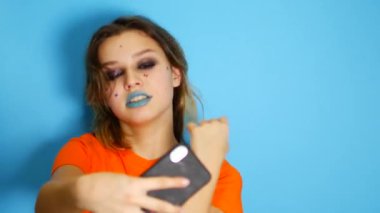 Mutlu kız gülüyor ve ellerini yüzüne kapalı, izole içinde dururken, mavi arka plan üzerinde tutmak uzun saçlı. Şaşırdım ve şok bir güzel genç kız duygu portresi, yaşam biçimi