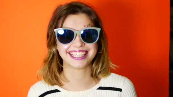 Chica Aburrida Con Gafas Sol Las Manos Sobre Fondo Naranja — Vídeos de Stock