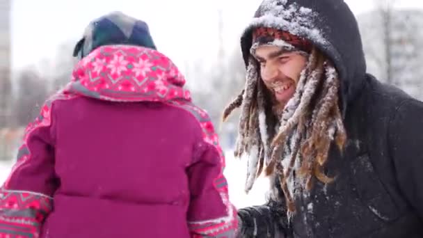 Guapo padre joven y su pequeña hija linda se divierten al aire libre en invierno. Disfrutando pasar tiempo juntos mientras hacen ángeles de nieve. Concepto familiar — Vídeo de stock