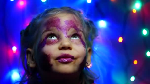 Fille de cinq ans sur le fond de guirlandes festives. Maquillage, paillettes, portrait — Video