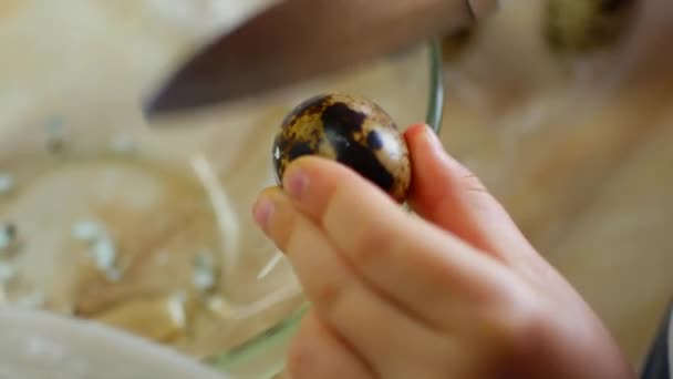 Ребенок разбивает перепелиное яйцо. помочь маме на кухне — стоковое видео