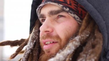 Genç gülümsemek kamera kış kar ormandaki adam. Beyaz Park adam açık havada yürüyüş